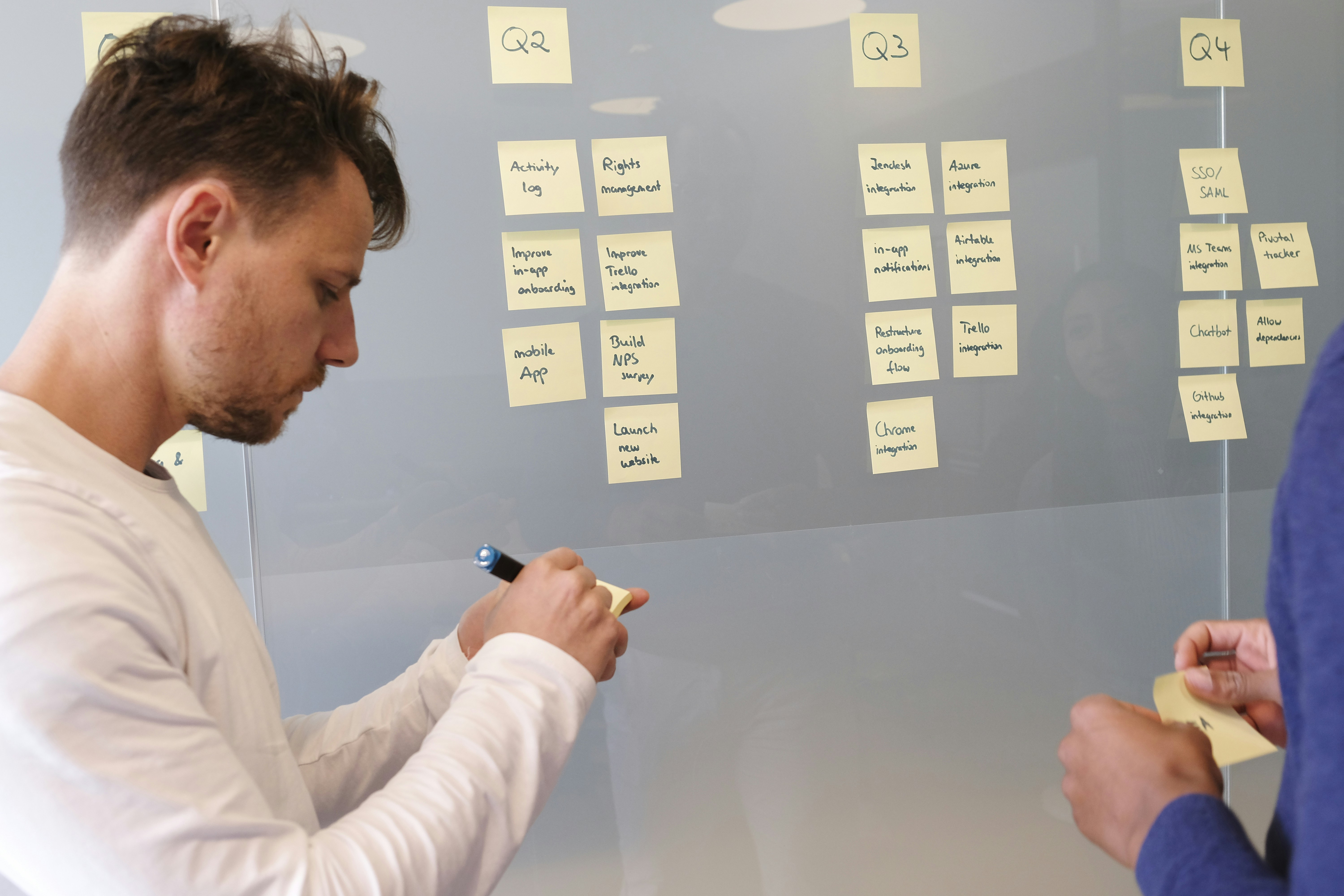 Man organizing sticky notes on a whiteboard representing the complexity of an over-accumulated tech stack versus a clear five-tool foundation