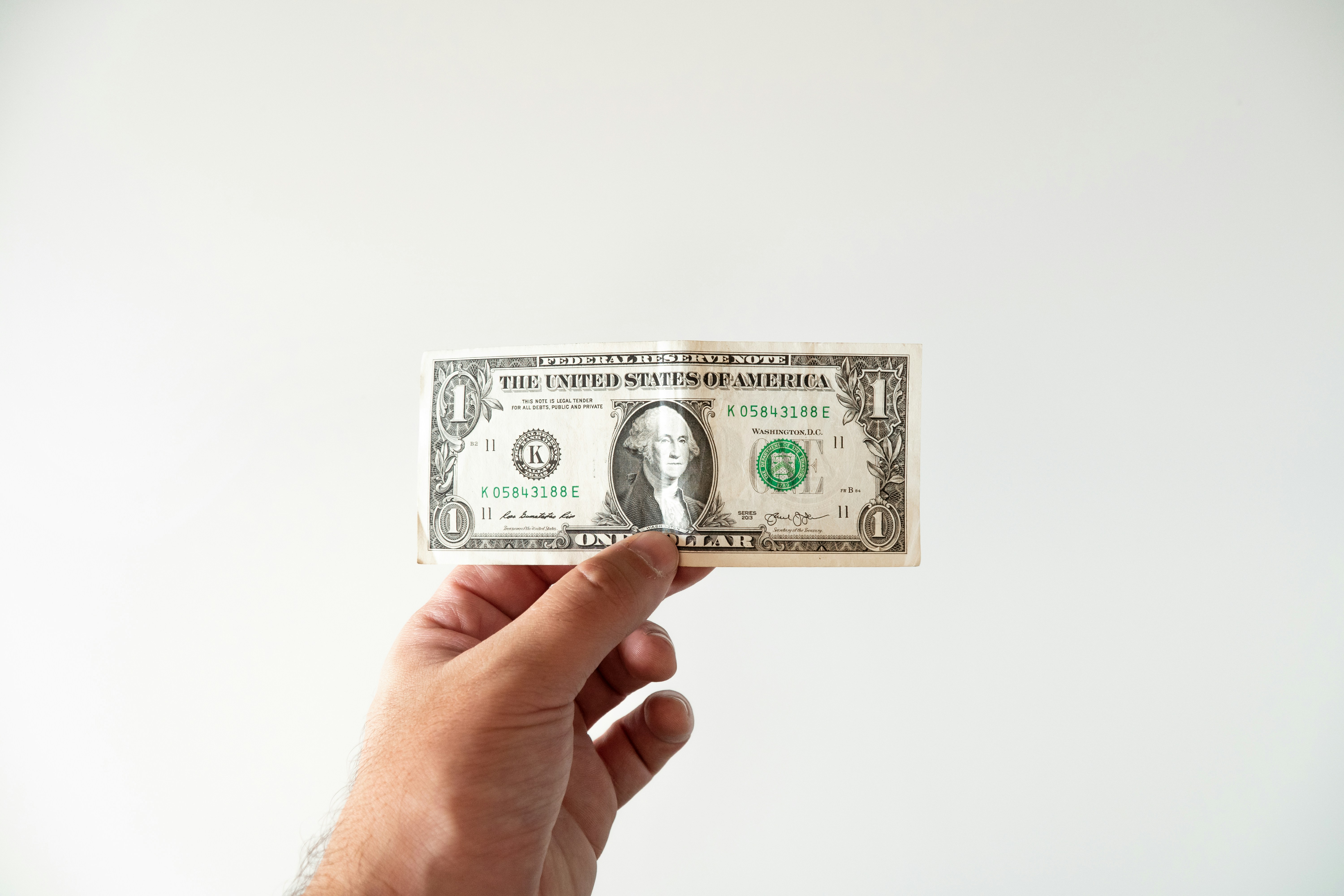 Hand holding a US dollar bill representing the true cost of misplaced customer loyalty
