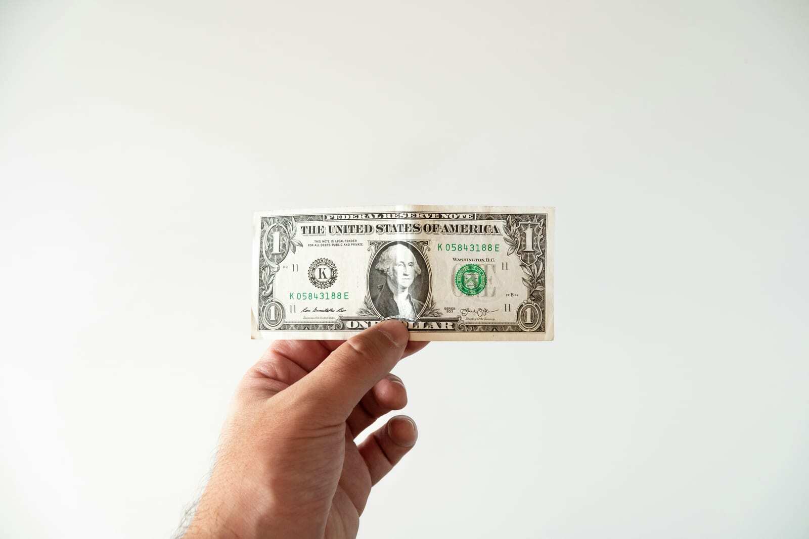 Hand holding a US dollar bill representing the true cost of misplaced customer loyalty
