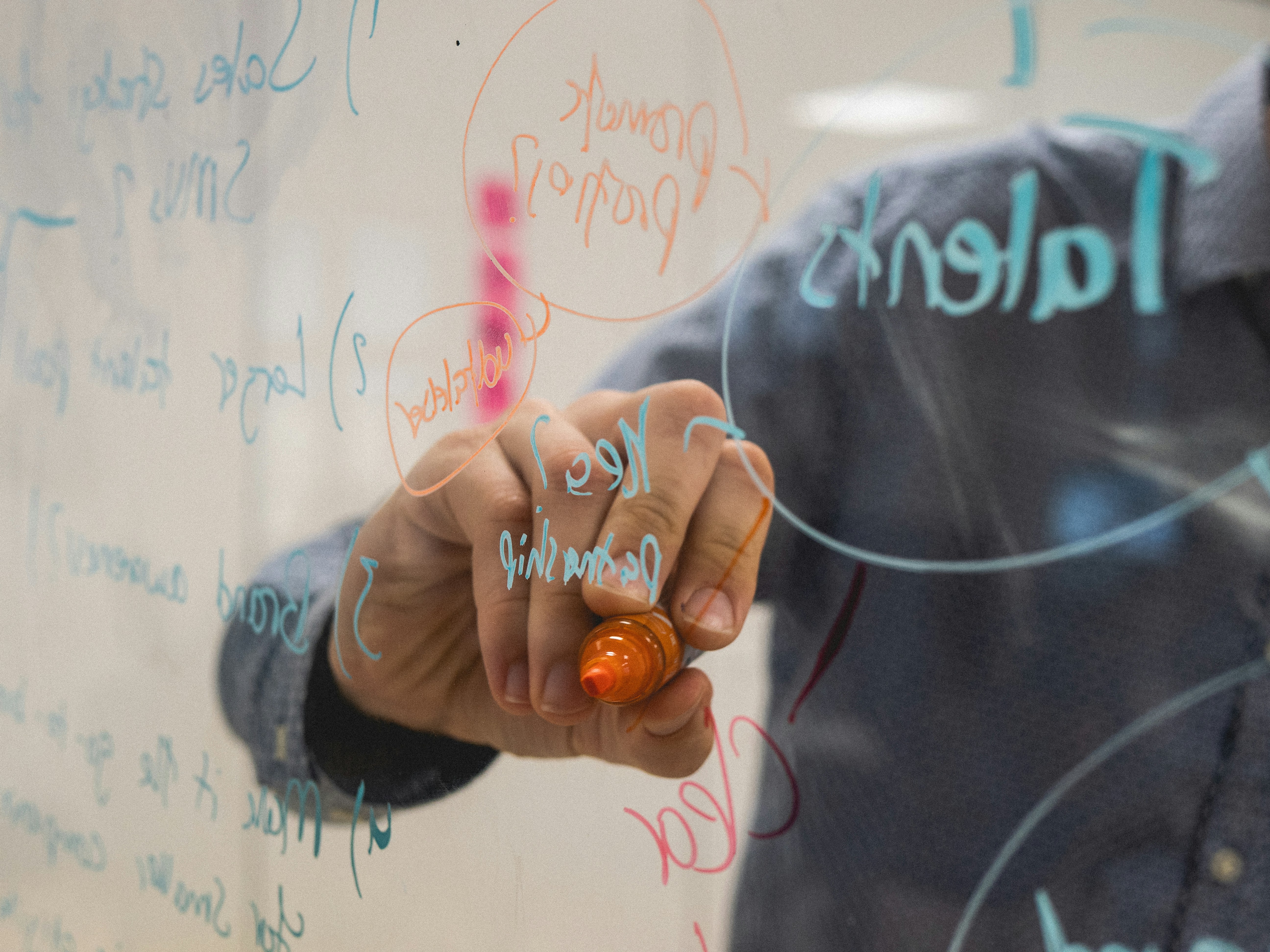 Business leader writing strategic framework on glass whiteboard during planning session